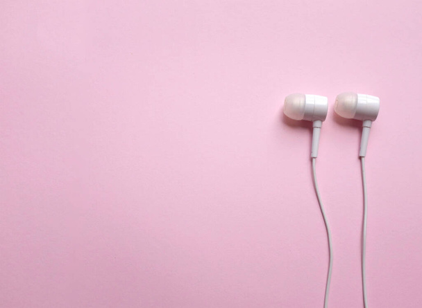 espacio de copia auriculares blancos, auriculares, auriculares con auriculares sobre fondo rosa pastel aislado - Foto, Imagen