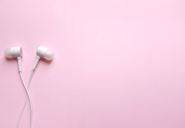Van een witte koptelefoon, oortelefoon, oordopjes met hoofdtelefoon op geïsoleerde roze pastelachtergrond - Foto, afbeelding