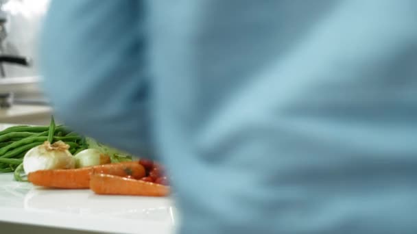 Een man die groenten op tafel snijdt. Concept van voedselbereiding thuis of in het restaurant. - Video