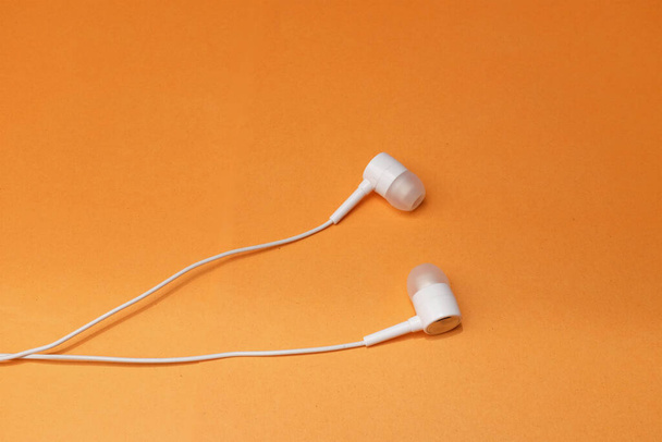 espaço de cópia fones de ouvido brancos, fone de ouvido, fones de ouvido com fone de ouvido em fundo laranja isolado - Foto, Imagem