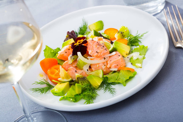 Tasty fish ceviche with chopped ripe avocado, juicy kumquat, lettuce leaves and dill on white plate.. - Foto, Imagem