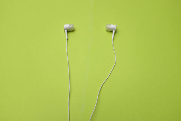 Von einem oben weißen Kopfhörer, Kopfhörer, Ohrhörer mit Headset auf isoliertem grünen, hellen Hintergrund - Foto, Bild