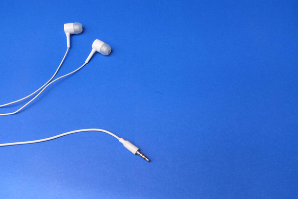 De auriculares blancos arriba, auriculares, auriculares con auriculares sobre fondo azul aislado - Foto, imagen