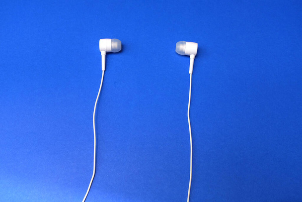 De auriculares blancos arriba, auriculares, auriculares con auriculares sobre fondo azul aislado - Foto, imagen