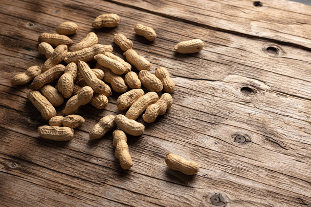 dried peanuts in pods on wooden background, close-up, place for text - 写真・画像