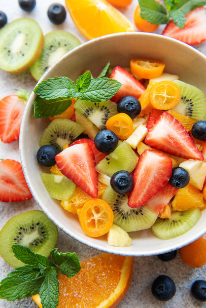 Здоровый салат из свежих фруктов в миске на деревянном фоне - Фото, изображение