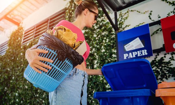 A young beautiful girl throws sorted garbage into special bins. - Photo, image