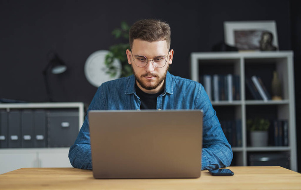 Portrait of young focused man coding on laptop, IT programmer working on creating innovative software, app, program. - Φωτογραφία, εικόνα