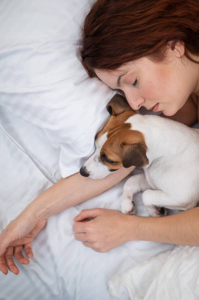 Caucasian woman is napping in bed hugging her beloved dog - Φωτογραφία, εικόνα