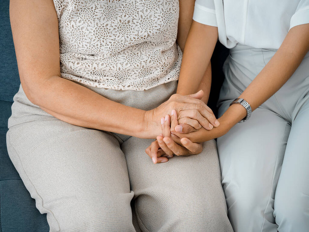 Close up of old mother, grandmother, elder or senior woman's hands hold her daughter or grandchild's hands for support with care and comfort. Giving love and encouragement concept. - Foto, Imagem