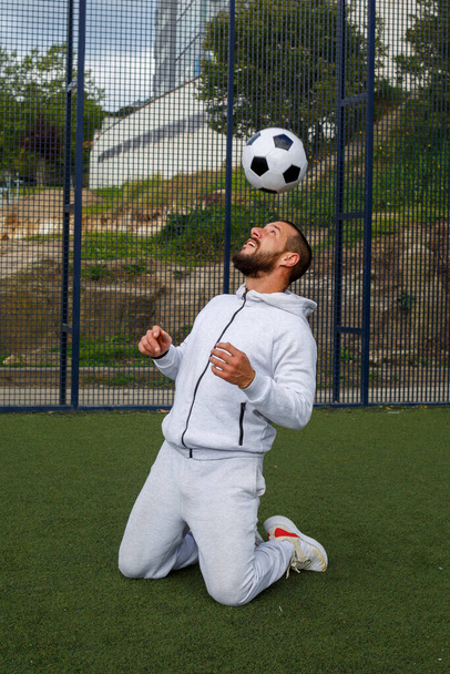 Fiatal férfi focista zsonglőrködik egy labdával a focipályán - Fotó, kép