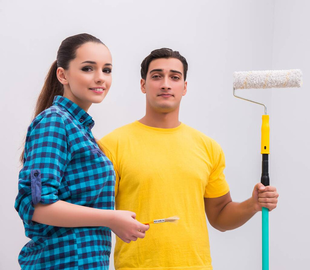 The young couple painting wall at home - Фото, зображення