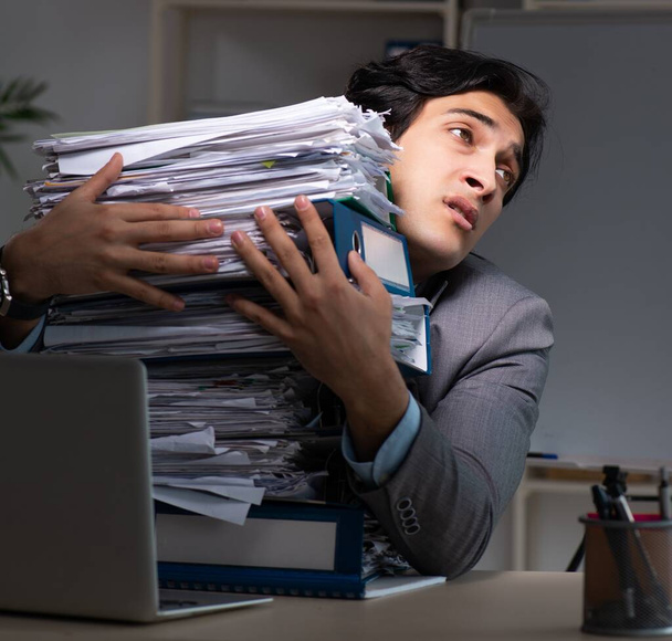 Joven empleado masculino trabajando hasta tarde en la oficina
 - Foto, Imagen