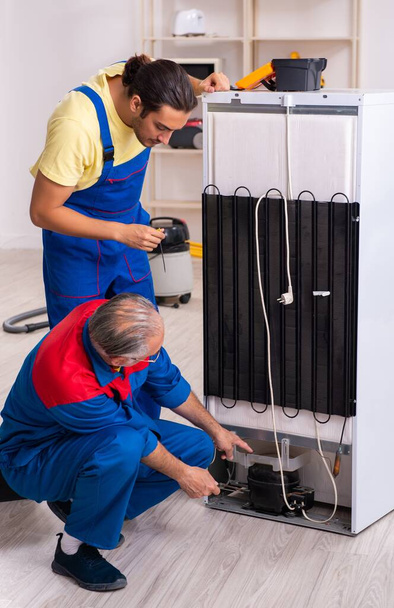 die beiden Auftragnehmer reparieren Kühlschrank in der Werkstatt - Foto, Bild
