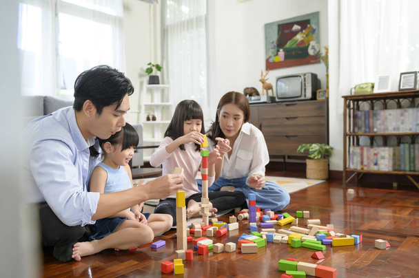 An Asian family with children playing and building tower of colorful wooden toy blocks in living room at home, Educational game. - Zdjęcie, obraz