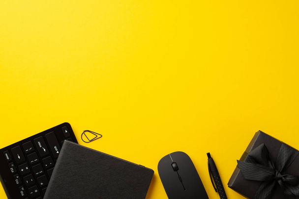 Kara Cuma indirim konsepti. Siyah hediye kutusunun üst görünümü kurdele yayı, not defteri bilgisayar faresi ve klavye boş arkaplan ile izole edilmiş sarı zemin üzerinde. - Fotoğraf, Görsel