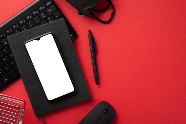 Kara Cuma konsepti. Akıllı telefon siyah hatırlatıcı kalem bilgisayar faresi klavye çantası ve izole edilmiş kırmızı arkaplan üzerindeki alışveriş arabasının üst görünümü boş alan - Fotoğraf, Görsel