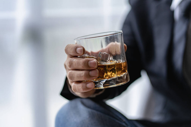 Közelkép egy komoly üzletemberről, aki egy pohár whiskey-bárral a kezében pihen és alkoholt iszik. - Fotó, kép