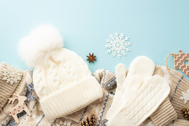 Koncept zimních prázdnin. Top pohled fotografie bílých rukavic bobble klobouk pletený jumper sněhové vločky borovice kužely anýzu a dřevěné ozdoby na izolovaném pastelově modrém pozadí - Fotografie, Obrázek