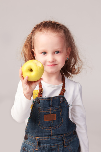 Pretty little girl holding apple in studio - Foto, Imagem