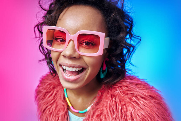Happy African woman in funky eyeglasses looking at camera while standing against colorful background - Φωτογραφία, εικόνα