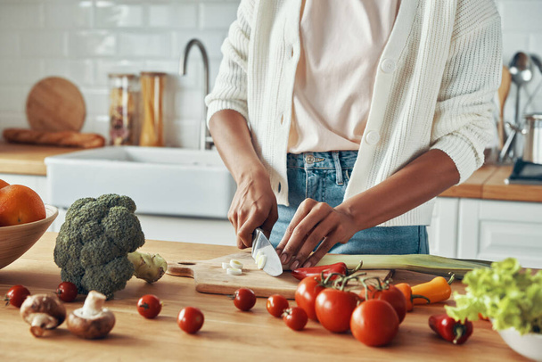 Крупним планом невизначена жінка, що ріже овочі на домашній кухні
 - Фото, зображення