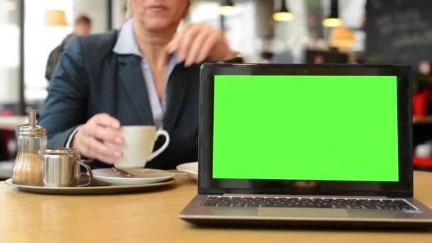 Notizbuch (Computer) Grüner Bildschirm - Frau mittleren Alters trinkt Kaffee im Café - Filmmaterial, Video