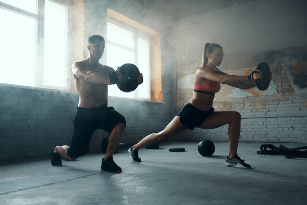 Young fit couple looking concentrated while doing weight training in gym - Foto, Imagem