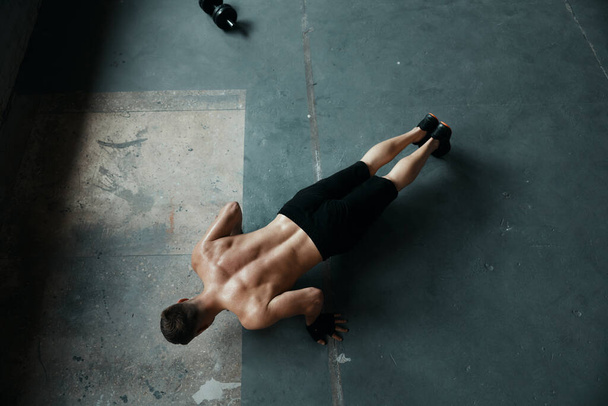 Top view of young muscular man doing push-up exercises in gym - Foto, afbeelding