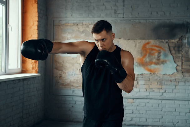 Confident young man practicing in punching while standing in gym - Фото, зображення