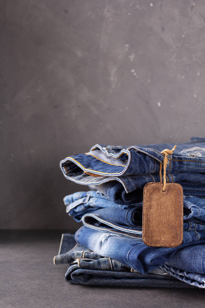Blue jeans denim heap at table background. Jeans fabric material and tag price label - Foto, Imagen