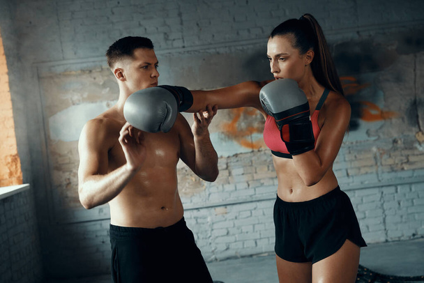 Fit young woman practicing in punching while her boxing coach teaching her - Zdjęcie, obraz