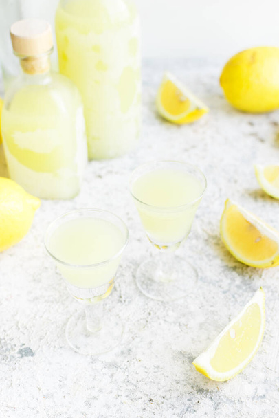 Traditional homemade lemon liqueur limoncello and fresh citrus on the table. Italian traditional liqueur limoncello with lemon. Italian alcoholic beverage. - Фото, изображение