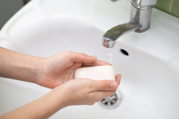 Lapsi käyttää saippuaa käsien pesuun. Henkilökohtaisen hygienian käsite - Valokuva, kuva
