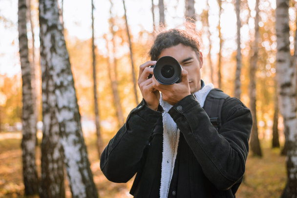 Portret młodego fotografa kręcącego pejzaże w jesiennym lesie - Zdjęcie, obraz