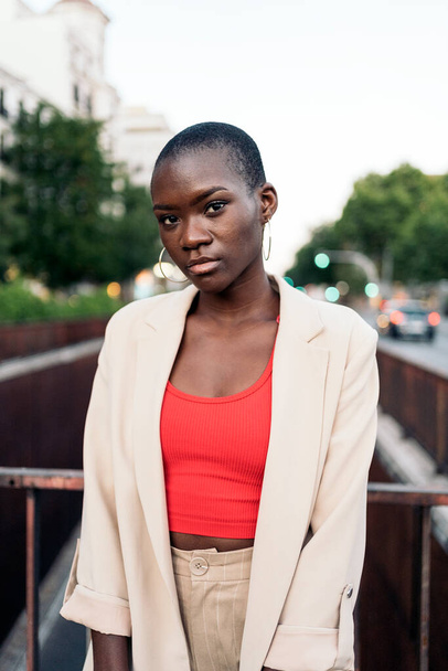 Portrait of an african american young woman with short hair standing and looking at camera on a footbridge in the city - Foto, afbeelding