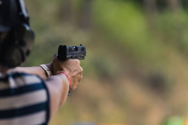 человек практикуется прицеливаться с пистолетом на стрельбище, средний крупный план размытый фон. Высокое качество фото - Фото, изображение