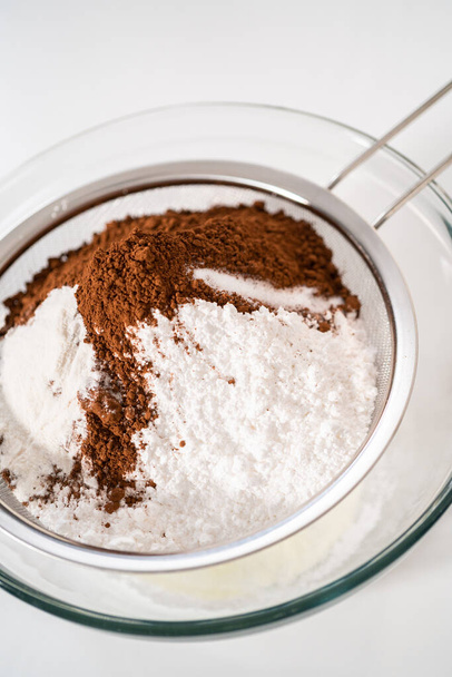 Sifting ingredients through hand sifter to make homemade hot chocolate mix. - Photo, image