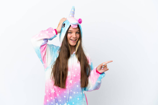Little caucasian girl wearing unicorn pajama isolated on white background surprised and pointing finger to the side - Zdjęcie, obraz