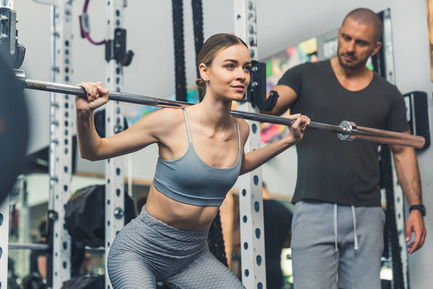 young woman lifting weights with the instructor at the gym, cowboy shot. High quality photo - Photo, Image