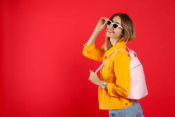 Happy woman with backpack on red background. Space for text - Φωτογραφία, εικόνα