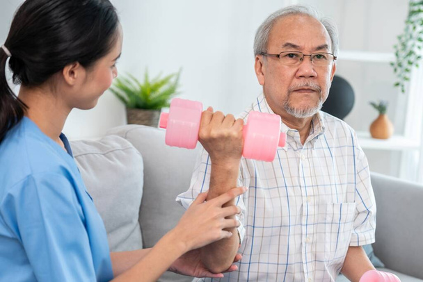 Unyielding senior patient doing physical therapy with the help of his caregiver. Senior physical therapy, physiotherapy treatment, nursing home for the elderly - 写真・画像