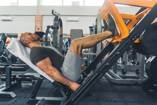 muskulöser Mann beim Training an der Beinpresse, Vollschuss. Hochwertiges Foto - Foto, Bild