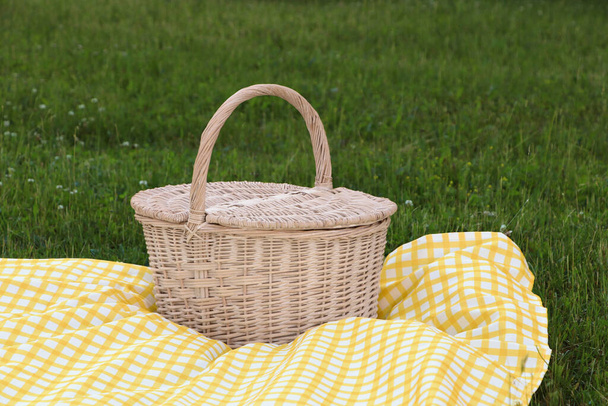 Picnic basket with checkered tablecloth on green grass outdoors - Zdjęcie, obraz