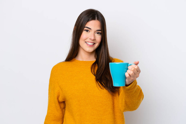 Young Brazilian woman holding cup of coffee isolated on white background with happy expression - Photo, Image