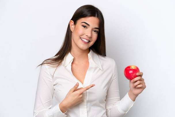 Young Brazilian woman with an apple isolated on white background and pointing it - Фото, изображение
