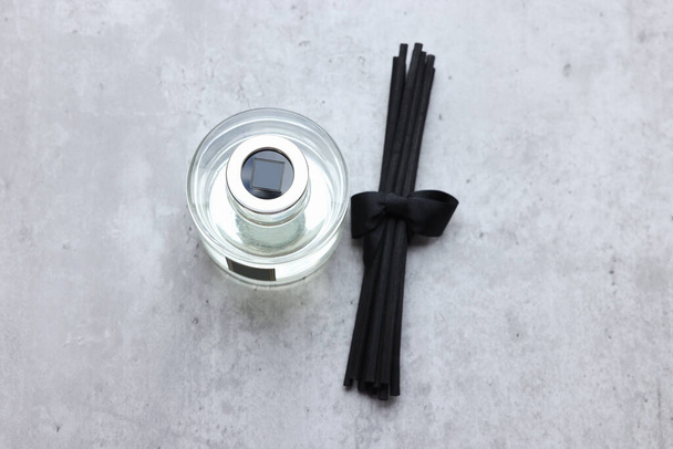 Reed sticks near glass bottle with aromatic liquid on gray marble table, flat lay - Foto, Imagen