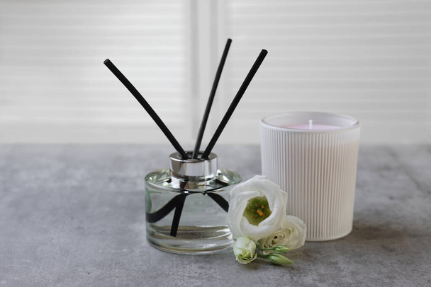 Reed diffuser, scented candle and eustoma flowers on gray marble table - Photo, image