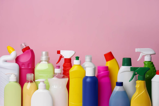 Many bottles of different detergents on pink background. Cleaning supplies - Foto, imagen