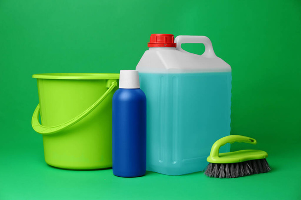 Bucket, cleaning supplies and tools on green background - Fotó, kép